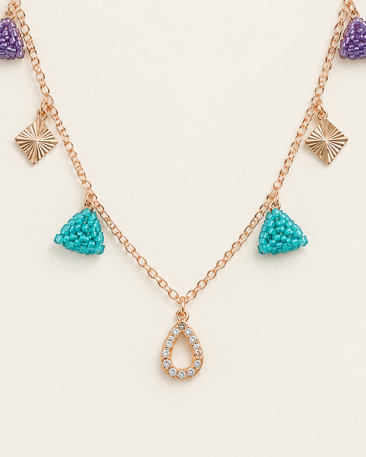 Close-up of turquoise beaded triangles, sunburst diamonds and the crystal teardrop drop on the Jewel Triangle Charm Necklace